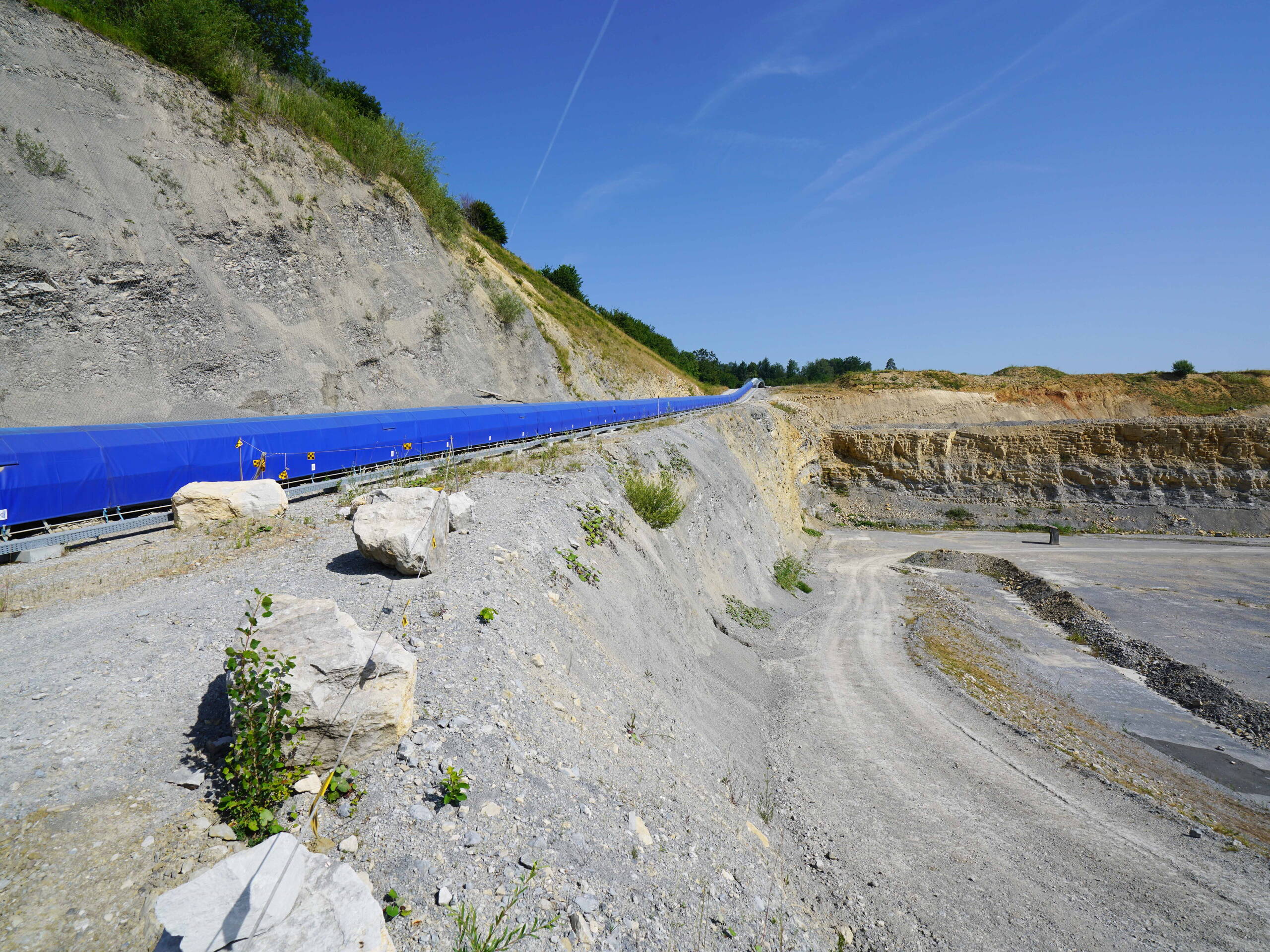 Die Zulieferung des Auffüllmaterials erfolgt über den bestehenden Bahnanschluss und wird von der Abladestelle über Förderbänder in den Steinbruch transportiert.