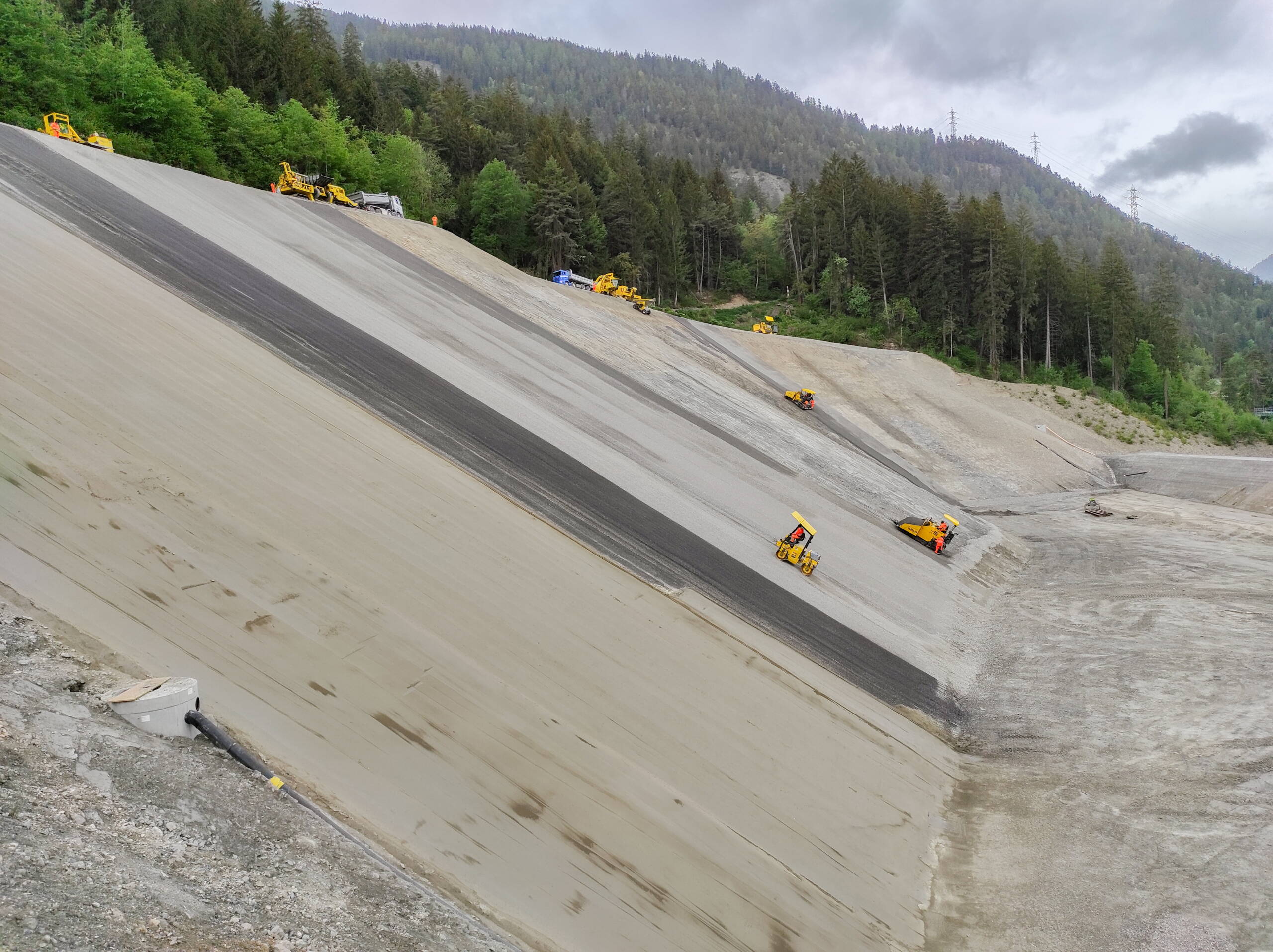 Einbau und Abwalzen Flächenfilter, im Vordergrund die eingebaute erste Schicht der geologischen Ersatzbarriere.