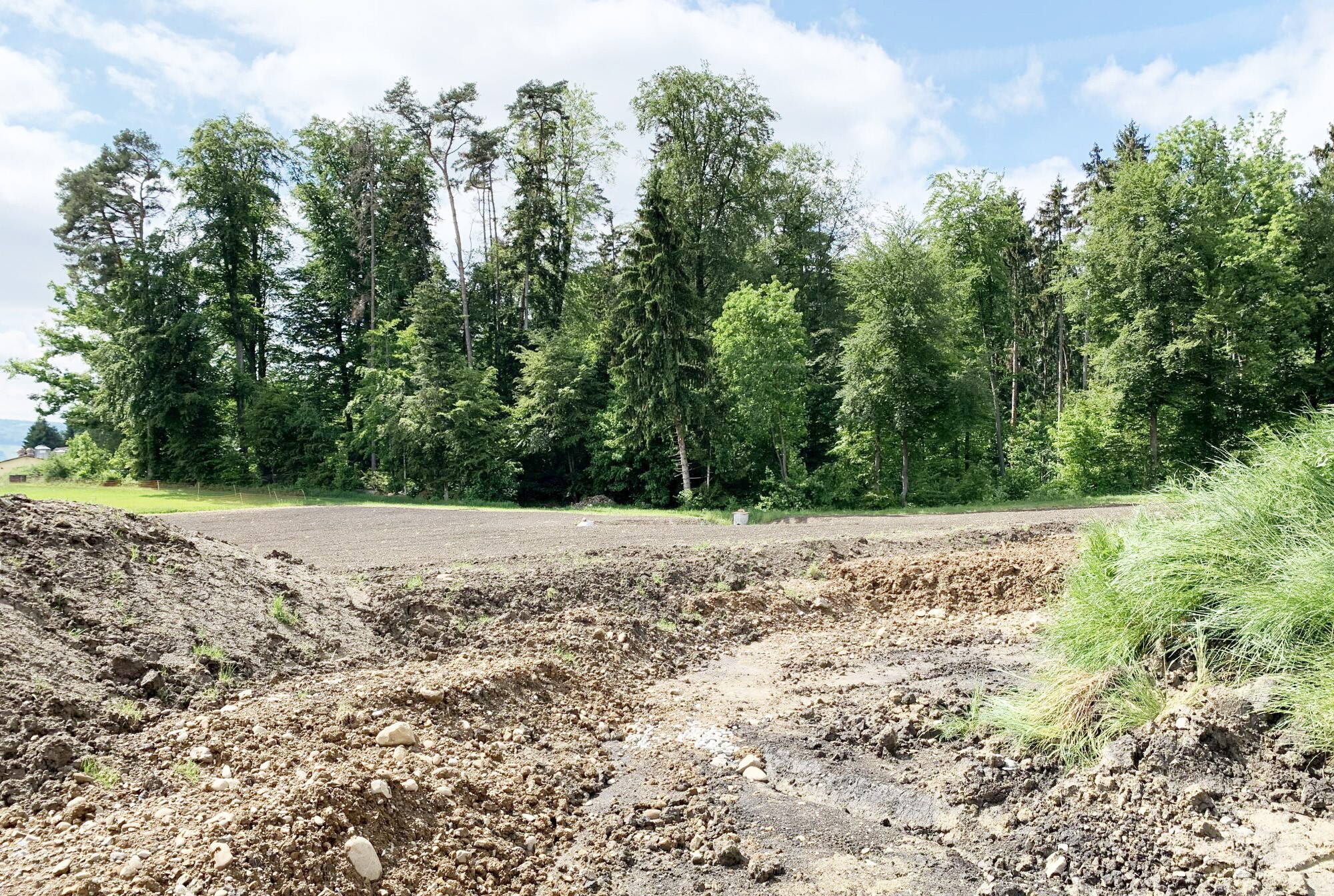 The topsoil and subsoil material is backfilled in strips using a crawler excavator.