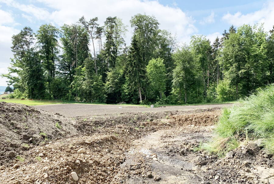 The topsoil and subsoil material is backfilled in strips using a crawler excavator.